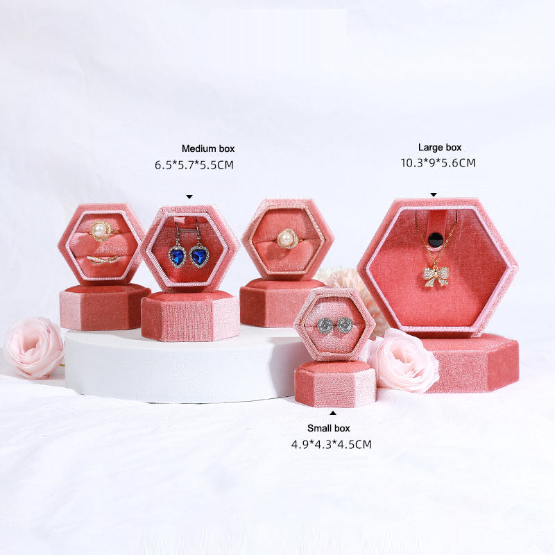 Hexagonal velvet jewelry box set in rose pink with open hex compartments holding necklaces and rings