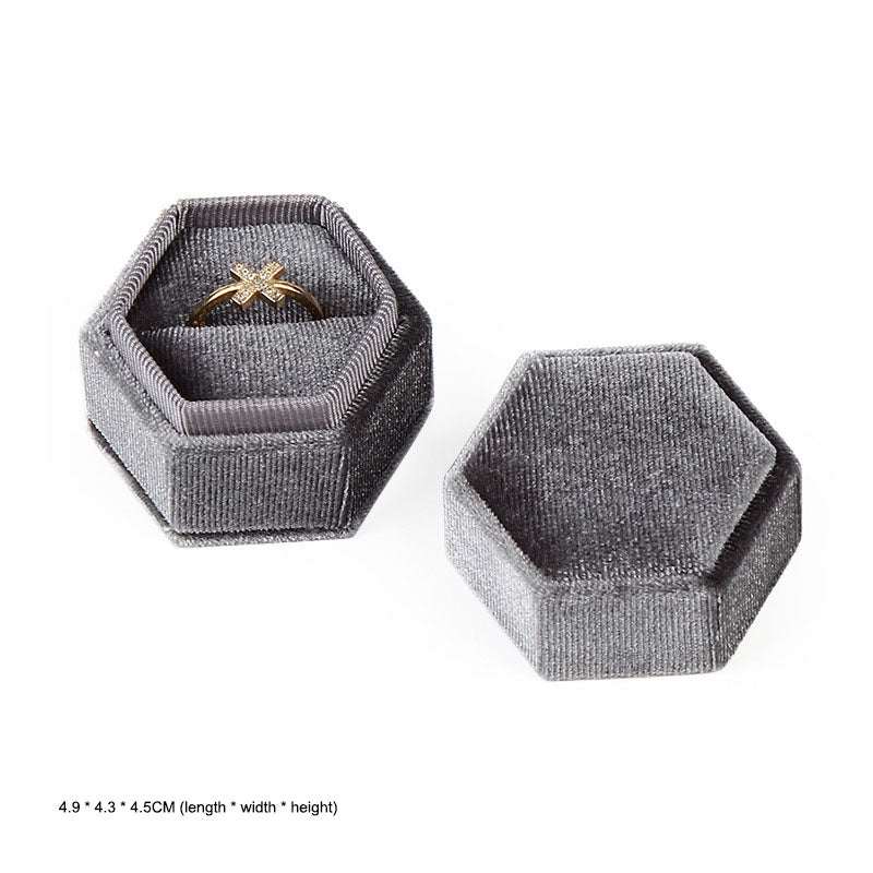 Hexagonal velvet ring jewellery box, gray, open with gold ring; closed box beside it