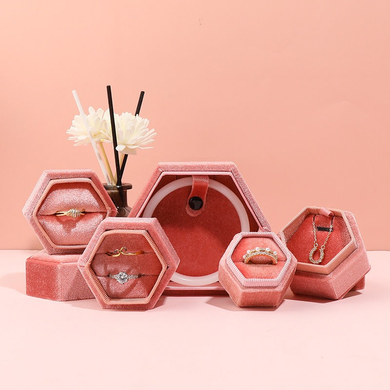 Hexagonal velvet jewelry box set in pink with open hex compartments holding jewelry