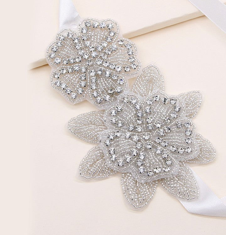 Layered rhinestone flower appliques on a white bridal headband