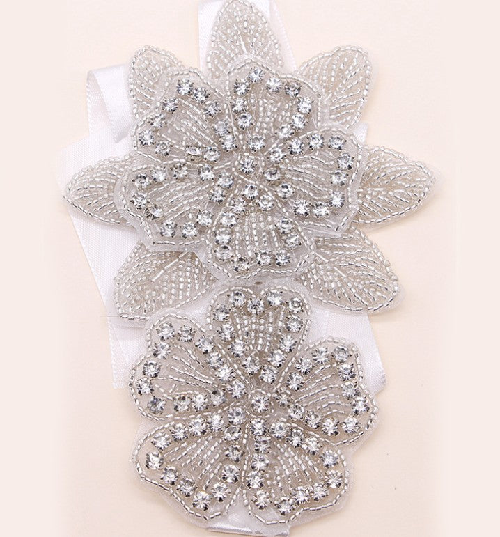 White ribbon headband with silver crystal flower and leaf centerpiece