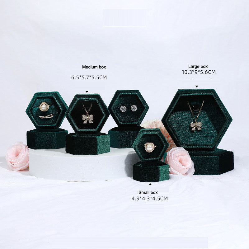 Hexagonal velvet jewelry box set in dark green with open hex compartments showing jewelry