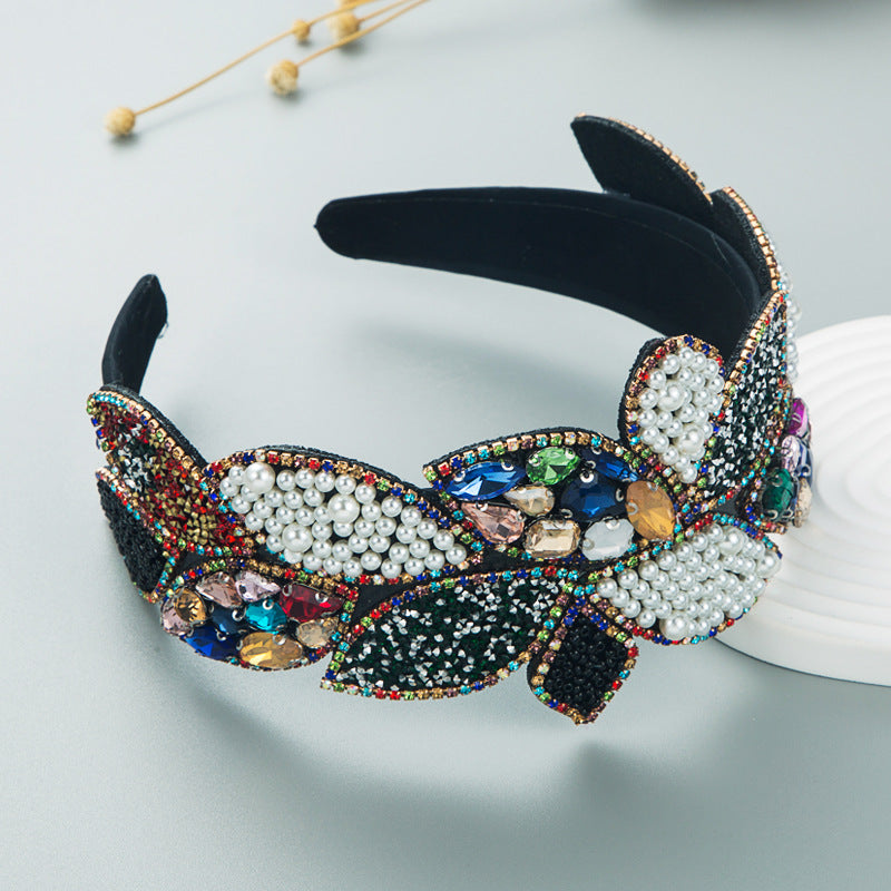 Wide pearl and rhinestone headband with multicolor gems and dark leaf accents
