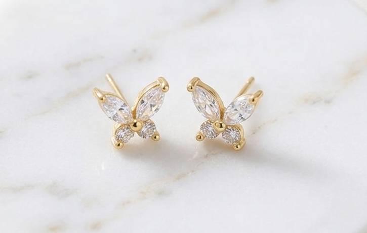 Gold butterfly stud earrings with clear rhinestone wings and small dangling stones