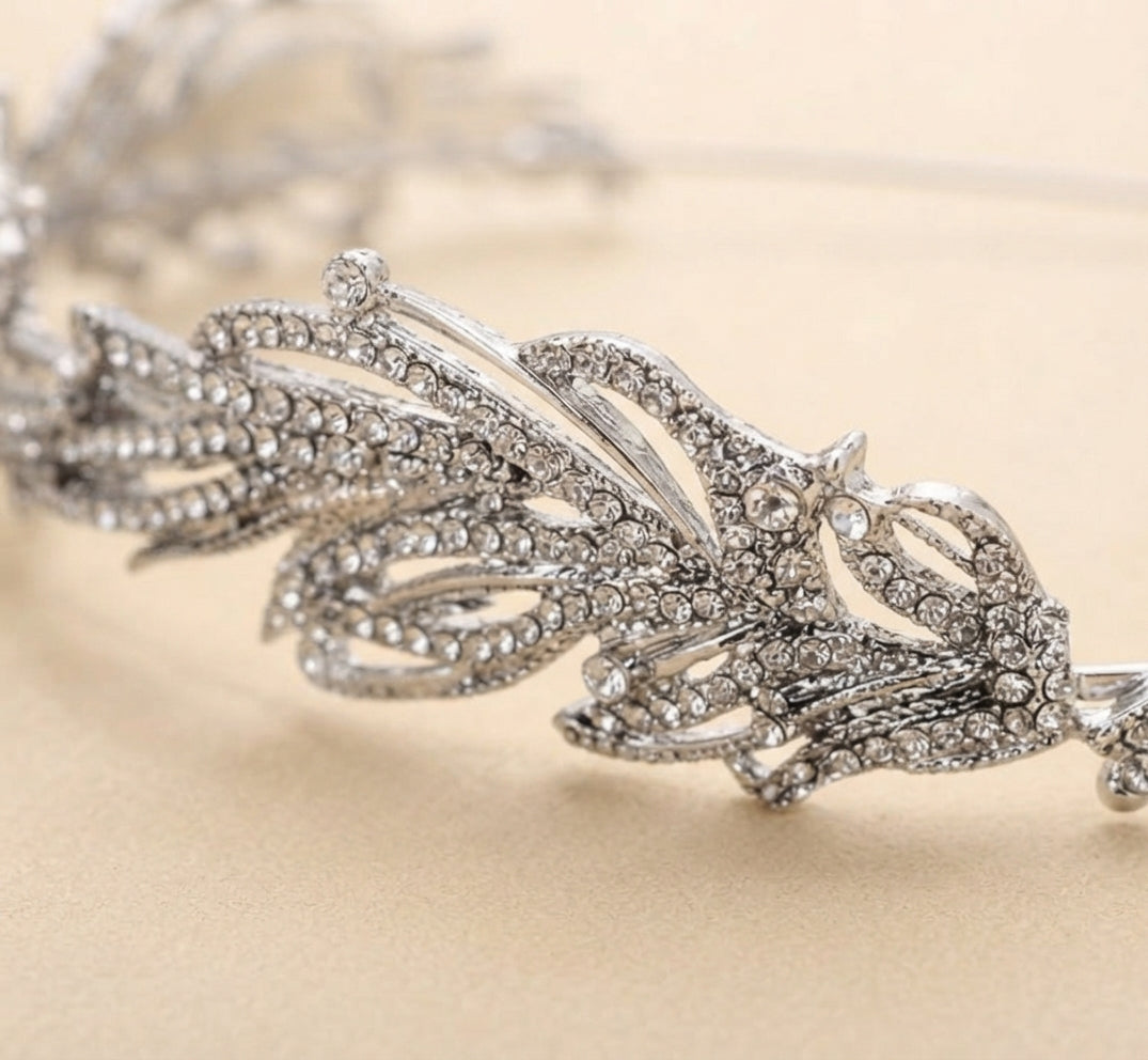 Close-up bridal headband with crystal leaf and swirl details, metal band prongs