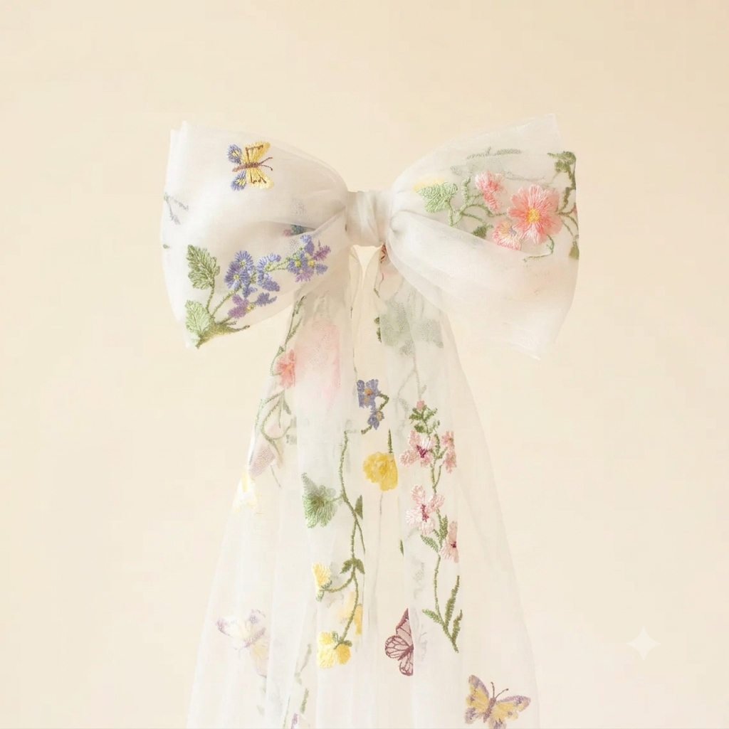 White tulle hair bow with embroidered flowers and butterflies and long sheer ribbon tails