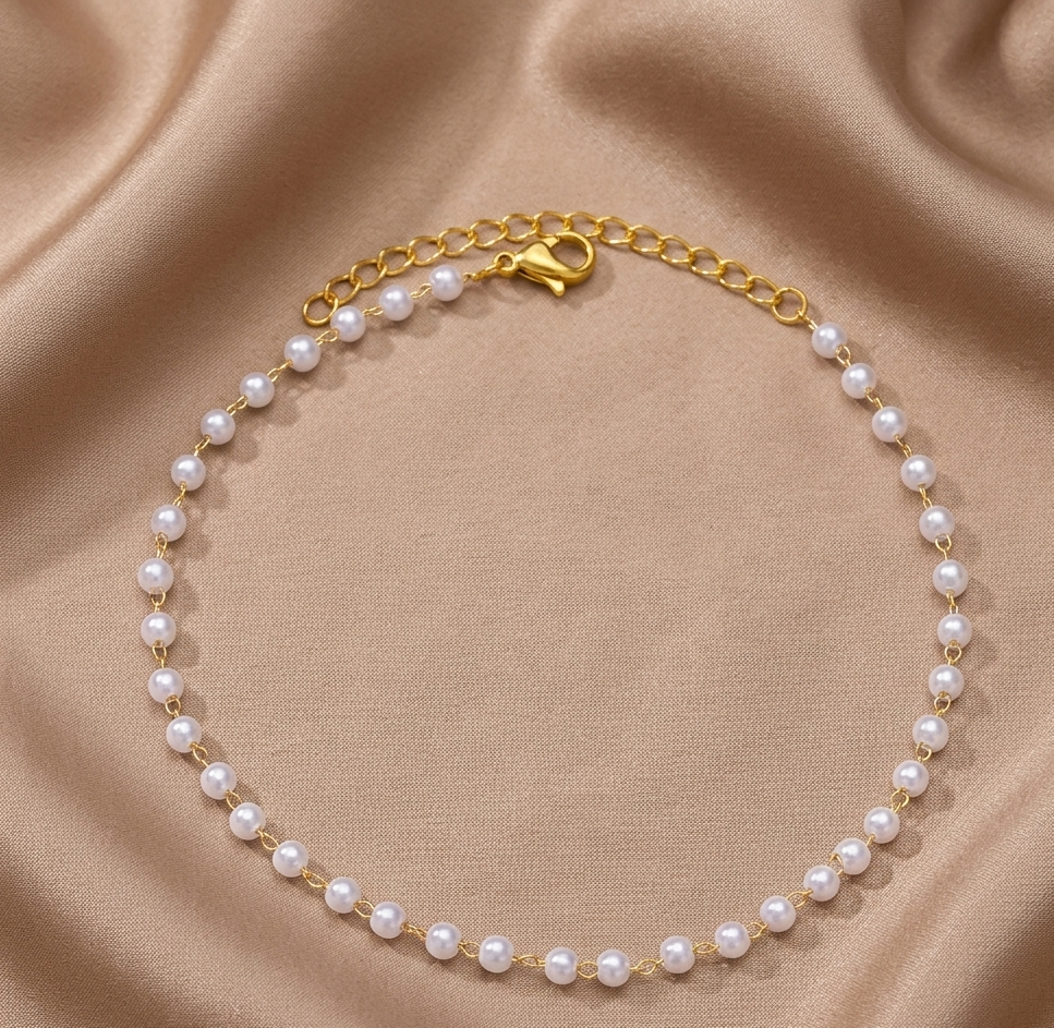 Gold chain pearl bracelet with evenly spaced white pearls along the band