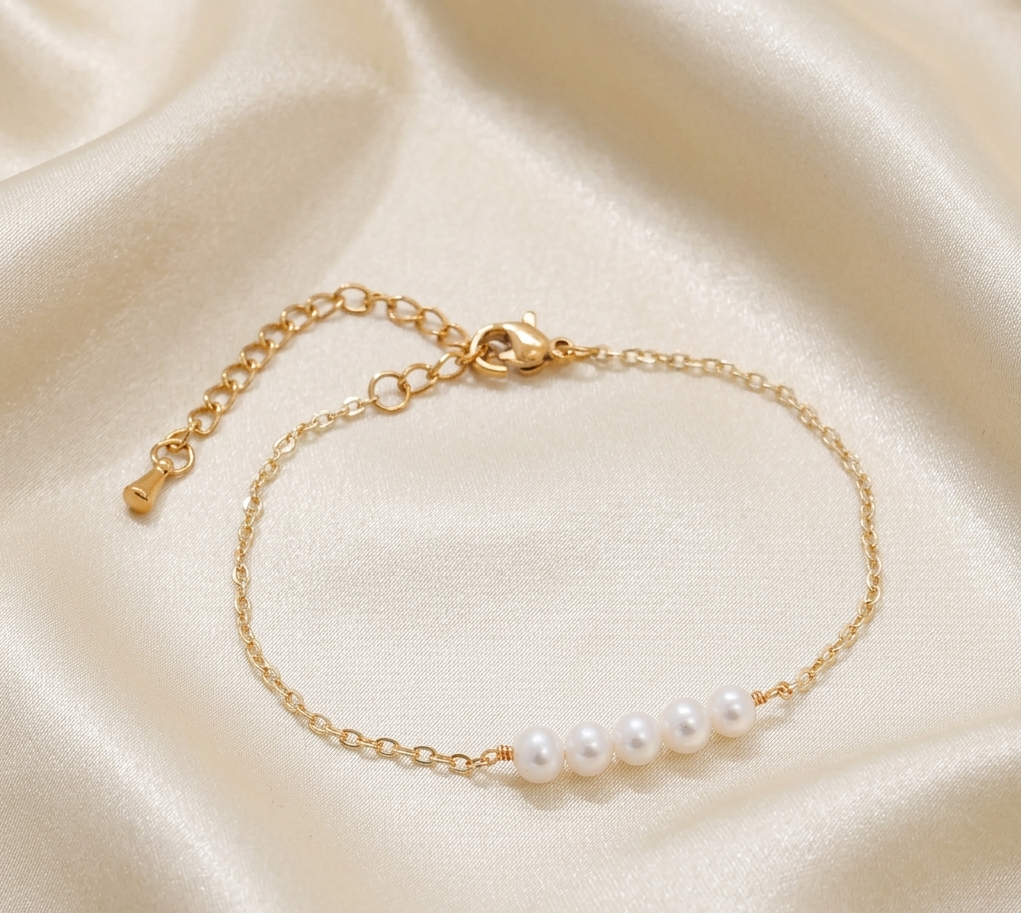 Gold link bracelet with white pearl row and small heart clasp detail