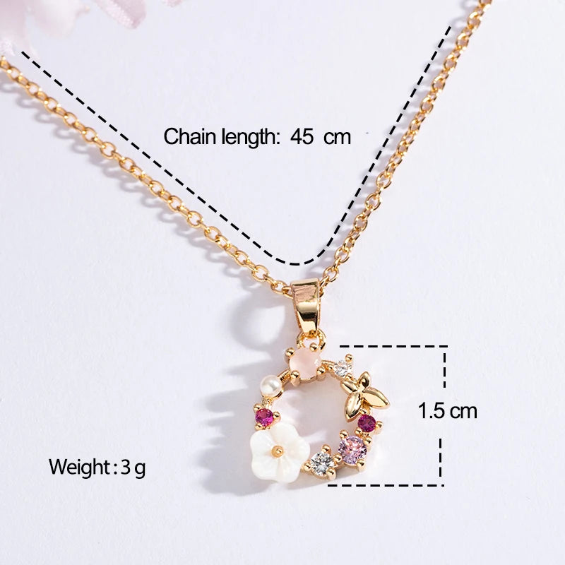 Gold floral wreath butterfly pendant necklace with white flower wreath and purple gems
