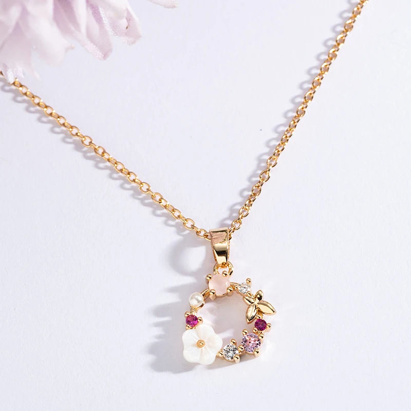 Gold floral wreath butterfly pendant necklace with white flowers and purple gem accents