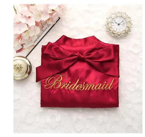 Red satin robe with embroidered “Bridesmaid” script and satin bow at the waist