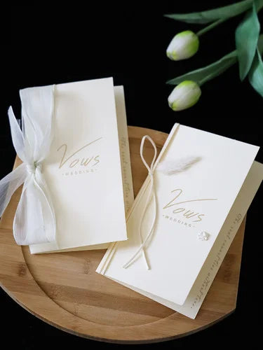 Ivory wedding vows booklet set with white ribbon ties and gold-toned lettering