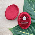 Red velvet ring box with diamond-style ring and slim silver band