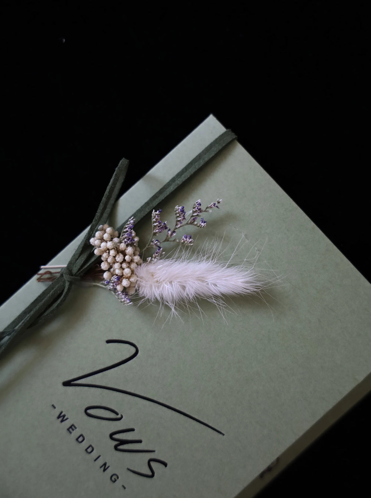 Sage green wedding vows booklet with feather bouquet embellishment and ribbon loop