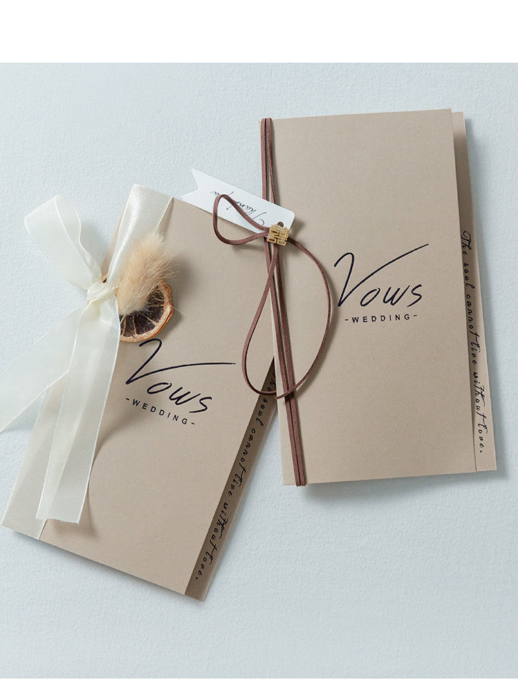 Ivory vow booklet set with gold “Vows,” bow ribbons, and small gold clasp ornament