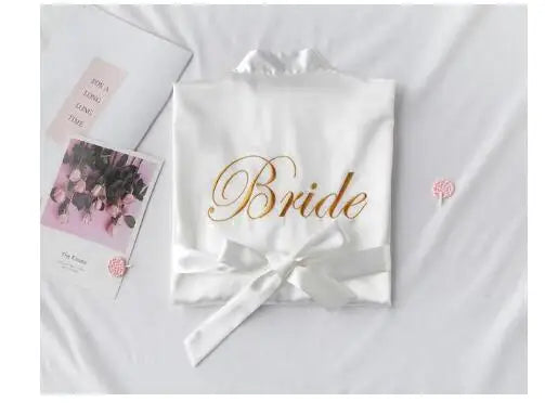 White satin robe with embroidered “Bride” script and a satin waist tie bow
