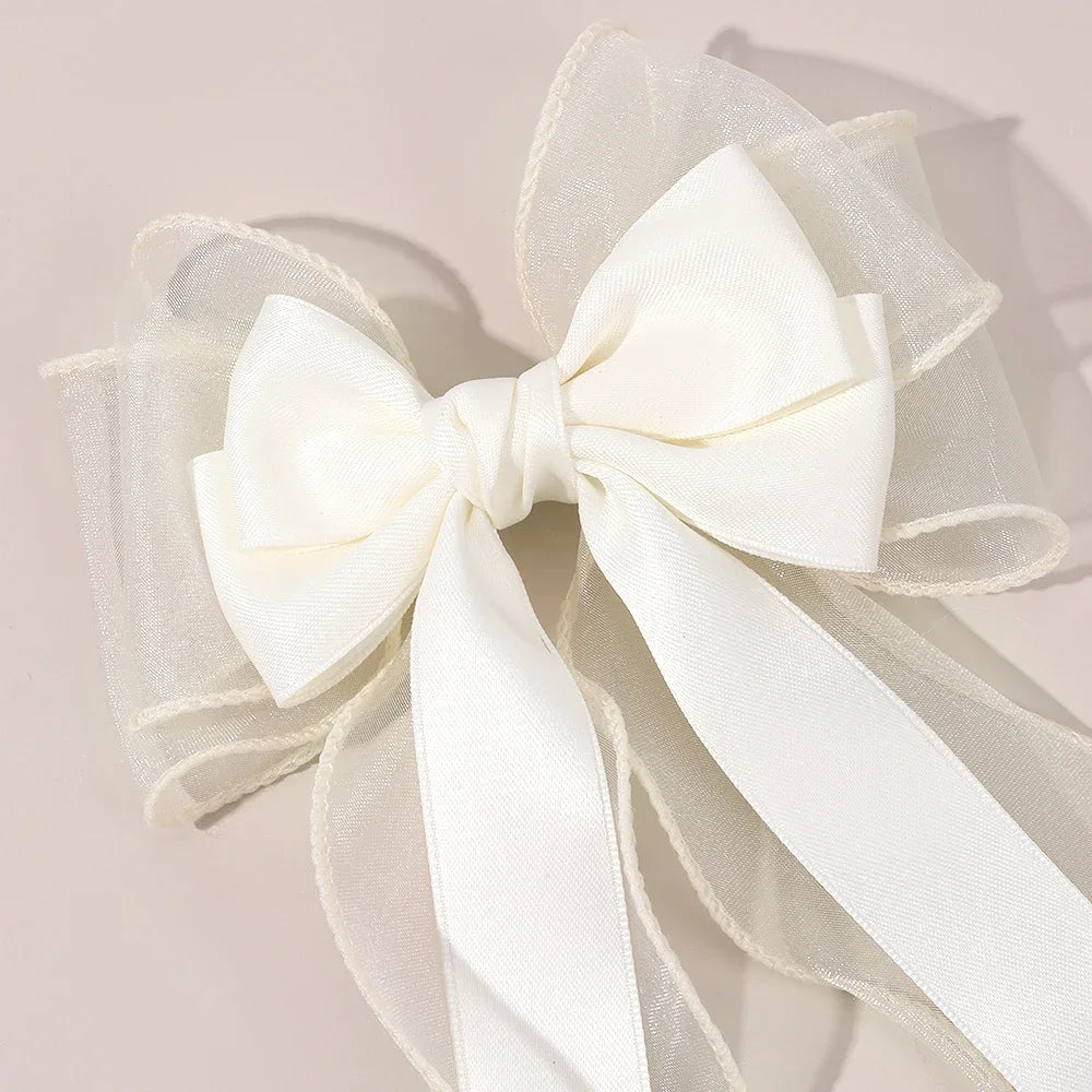 White chiffon bow hair clip close-up with layered sheer ribbons and bow center