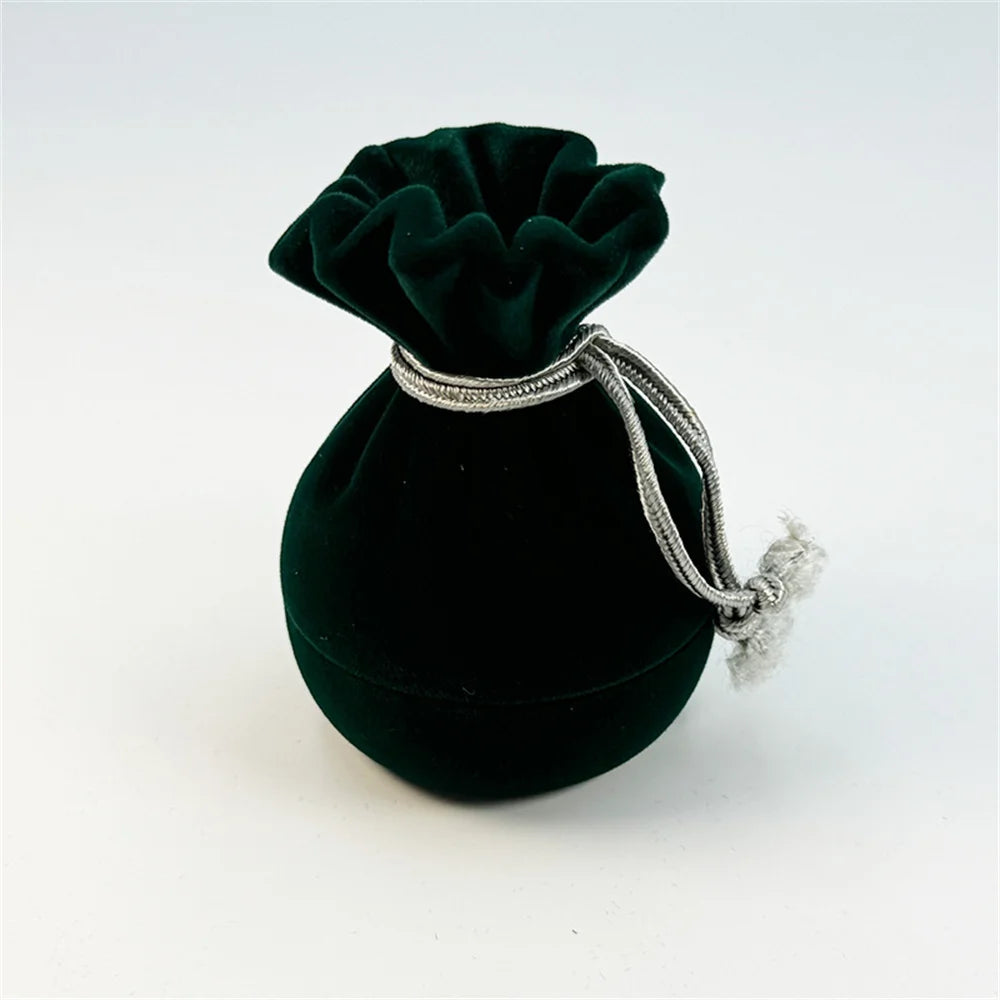 Green velvet ring pouch with pleated top and silver-toned drawstring cord ends.