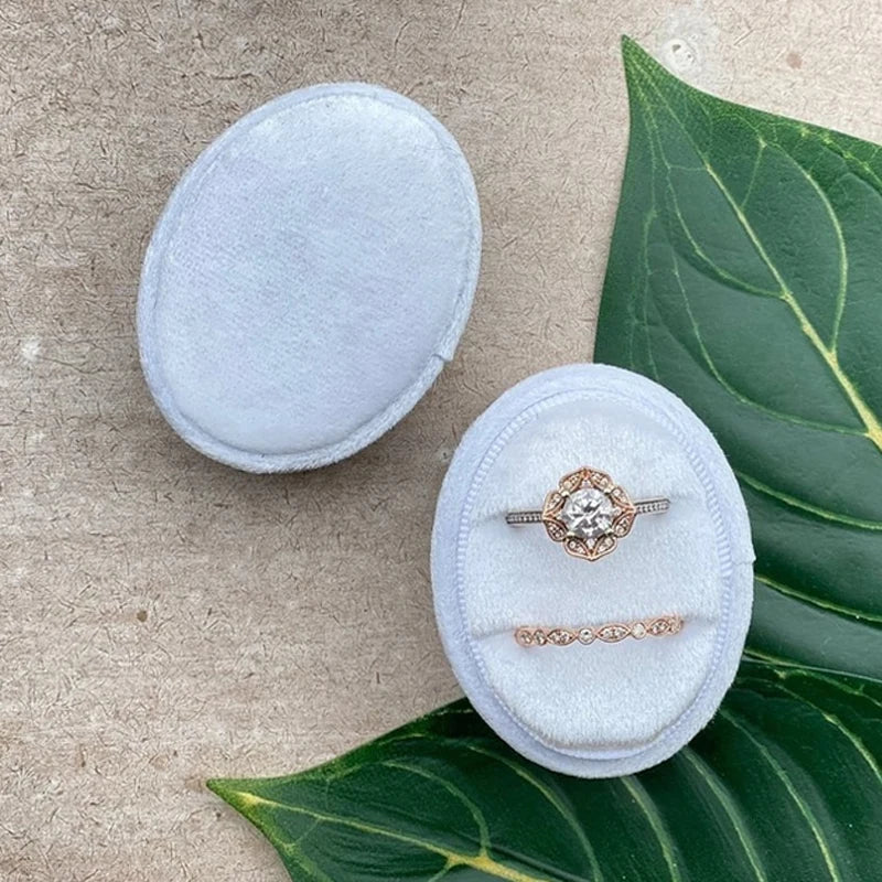 White velvet ring box with diamond-style ring and delicate matching band