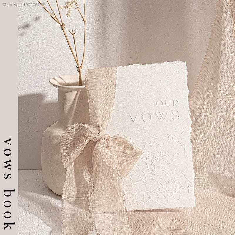 Embossed wedding vow booklet with cream organza ribbon bow, 'Our Vows' on cover