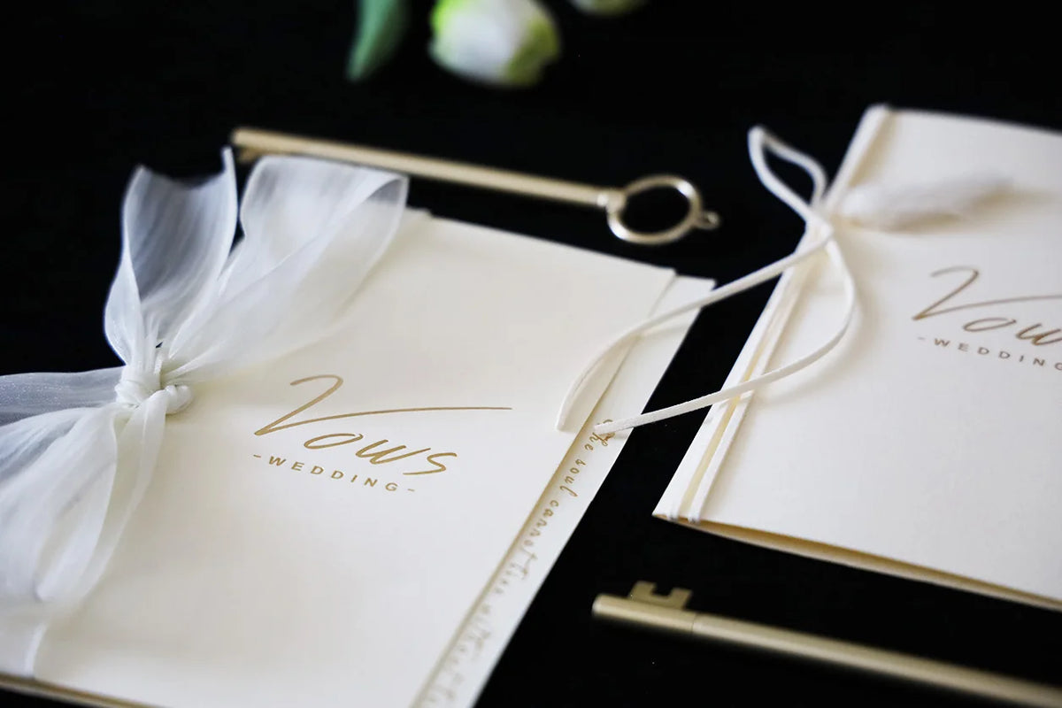 Ivory wedding vows booklet set with gold foil-style print and ribbon ties