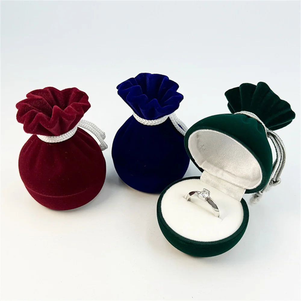 Velvet ring pouch set: red, blue, and green drawstring pouches; green holds a ring.