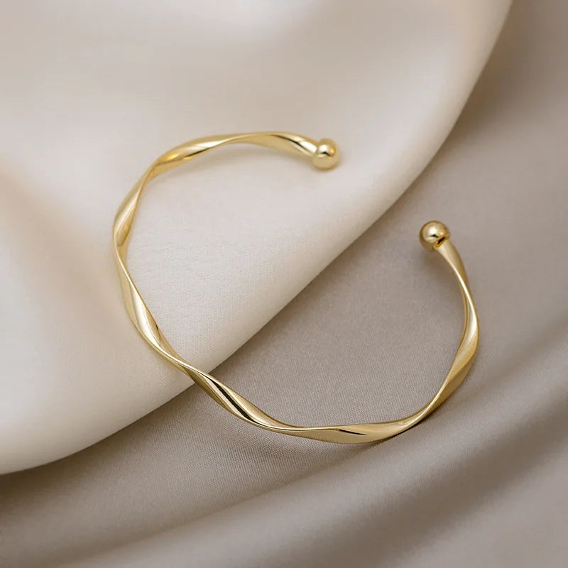 Gold twisted ribbon sculptural cuff bracelet with two ball ends