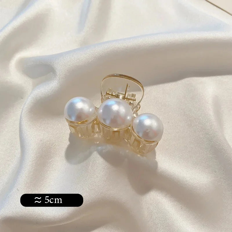 Pearl claw hair clip with gold-tone frame and white faux pearls; ~5cm.