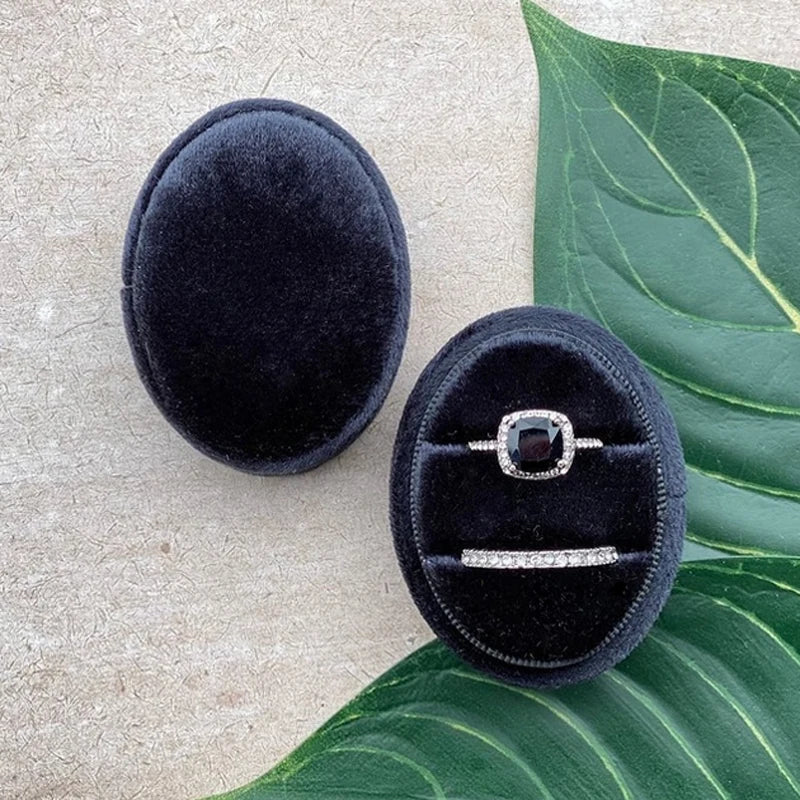 Dark navy velvet ring box with solitaire-style ring and slim band