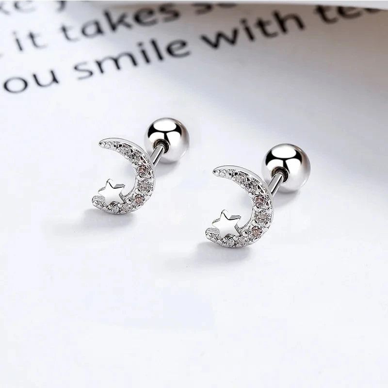 Silver huggie hoop earrings with crystal crescent moon and star accents