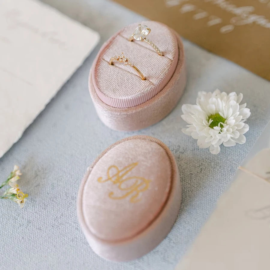 Blush pink velvet ring box with monogram initials and two rings inside