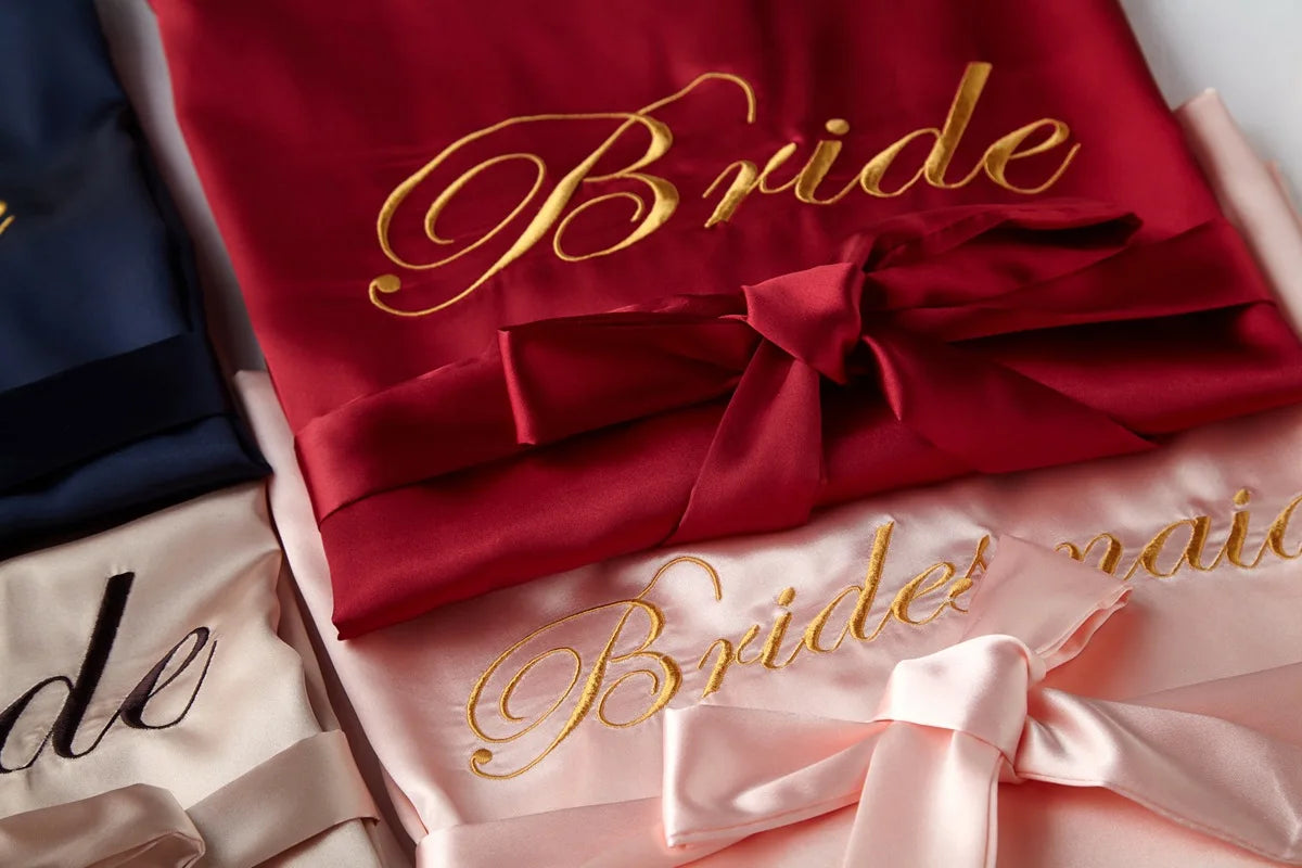 Satin bridal robe stack, red satin with gold “Bride” script and bow ties