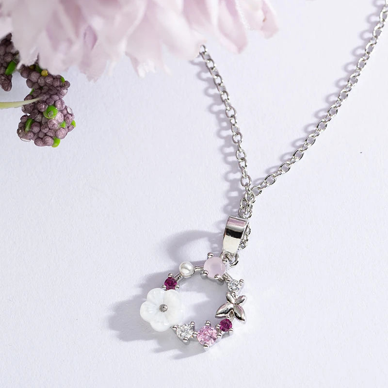 Silver floral wreath butterfly pendant necklace with white blooms and purple gemstone accents