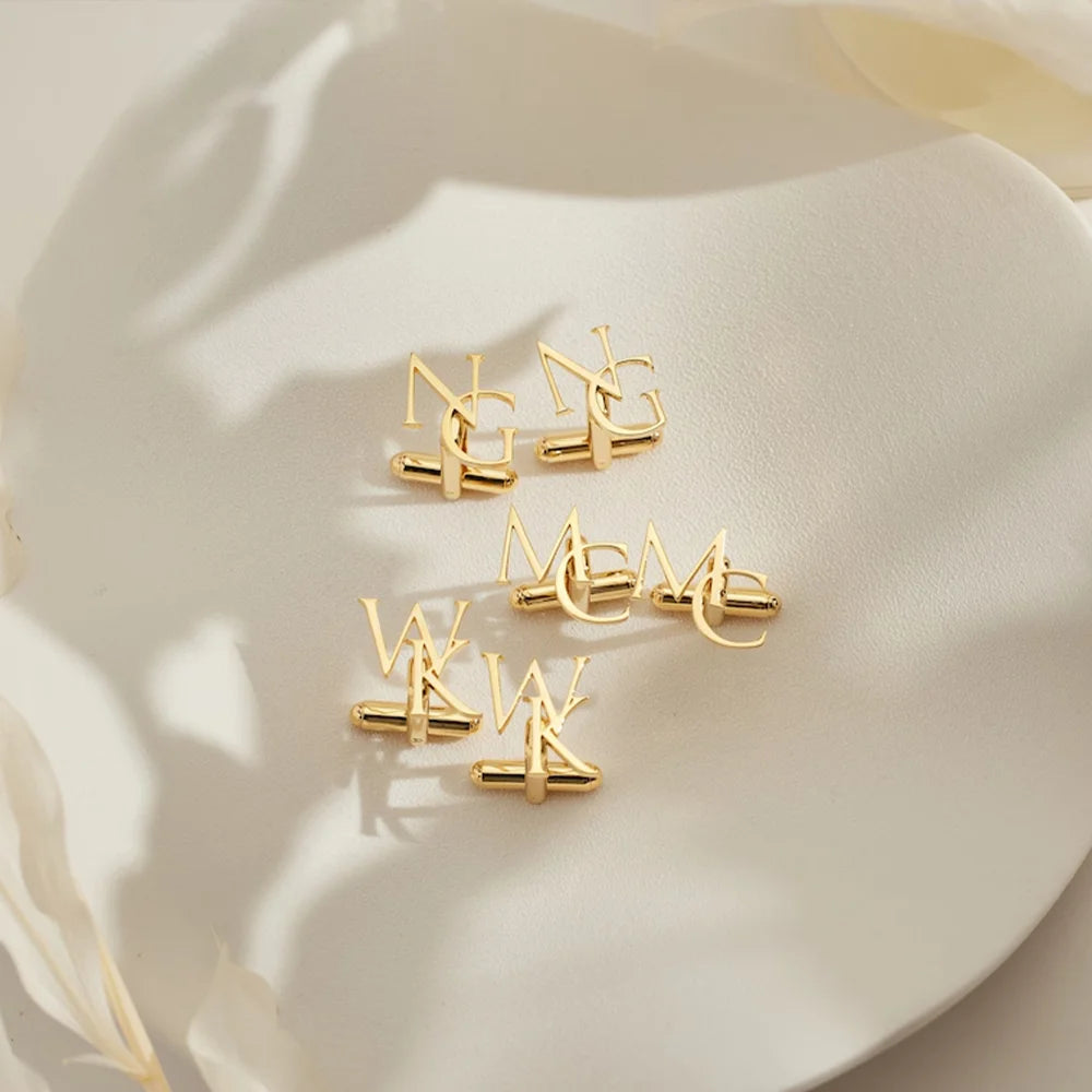 Gold monogram cufflinks with interlocking initial letters, polished metal pair