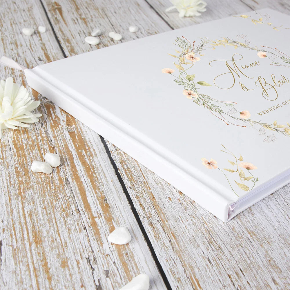 Wedding guest book close-up, floral wreath cover with personalized names, white with gold details