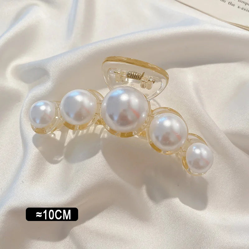 Pearl claw hair clip with gold-tone frame and white faux pearls; ~10cm.