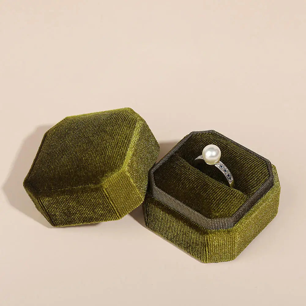 Olive octagonal velvet ring box set open with a pearl ring inside