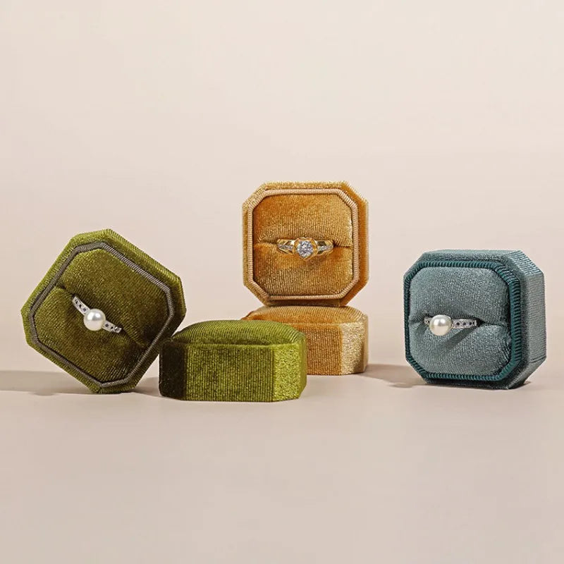 Octagonal velvet ring box set with open compartments in olive, tan, and teal