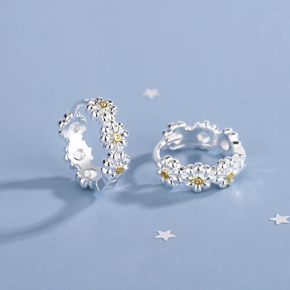 Silver-tone huggie hoop earrings with daisy and small gold accents