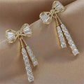 Gold-tone bow stud earrings with dangling crystal tassel drops
