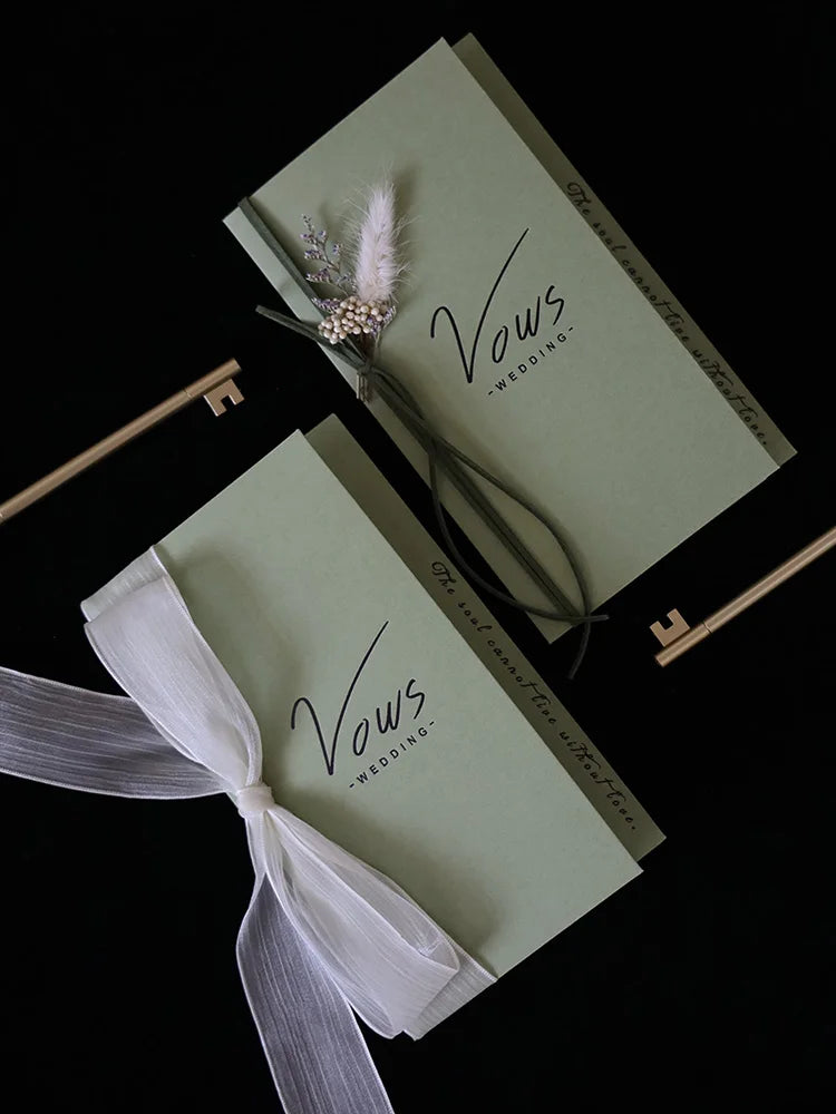 Sage wedding vows booklet set with matching ribbon bows and feather floral accents