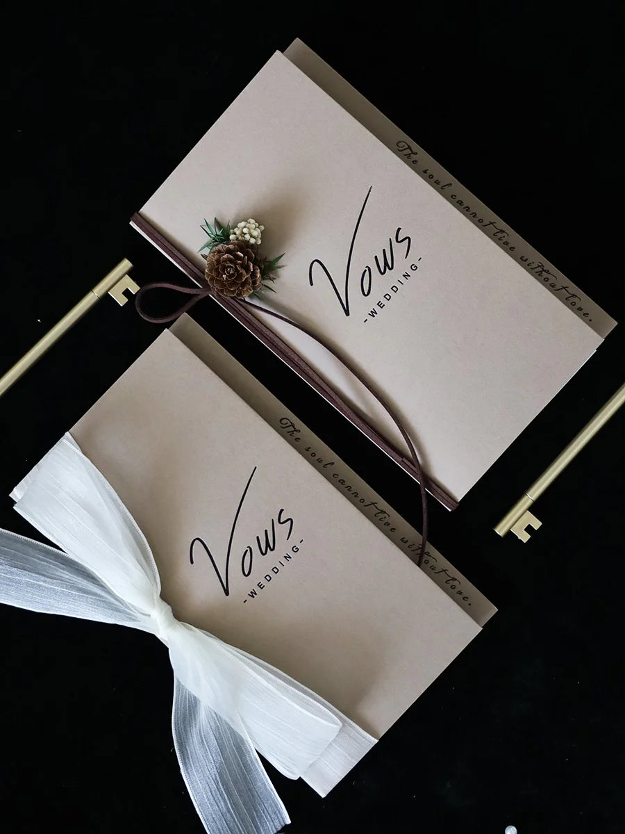 Ivory vows booklet set with gold-foil “Vows Wedding,” tied with dark ribbon and keepsake keys