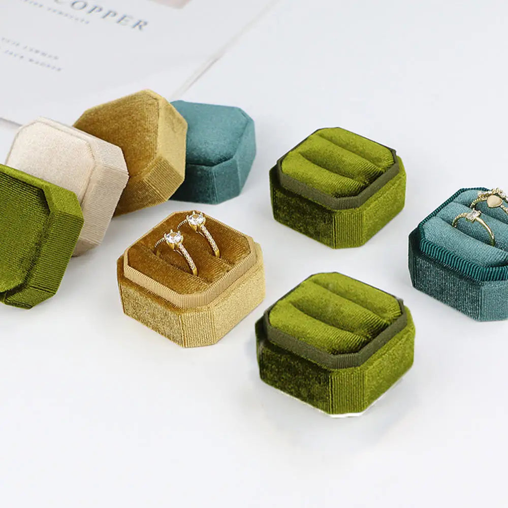 Octagonal velvet ring boxes in multiple colors with open lids and rings inside