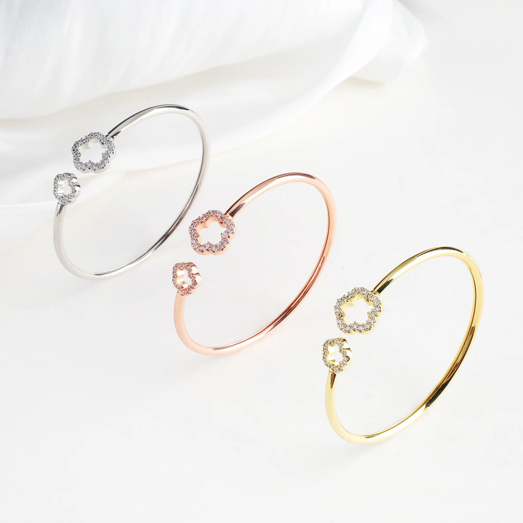 Silver open cuff bangle with two zirconia clover charms on an oval bracelet