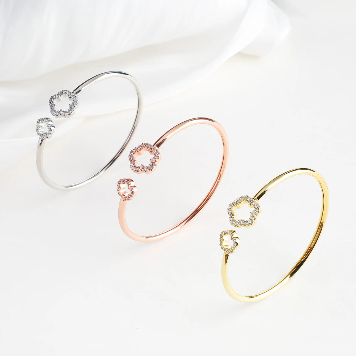 Silver open cuff bangle with two zirconia clover charms on an oval bracelet