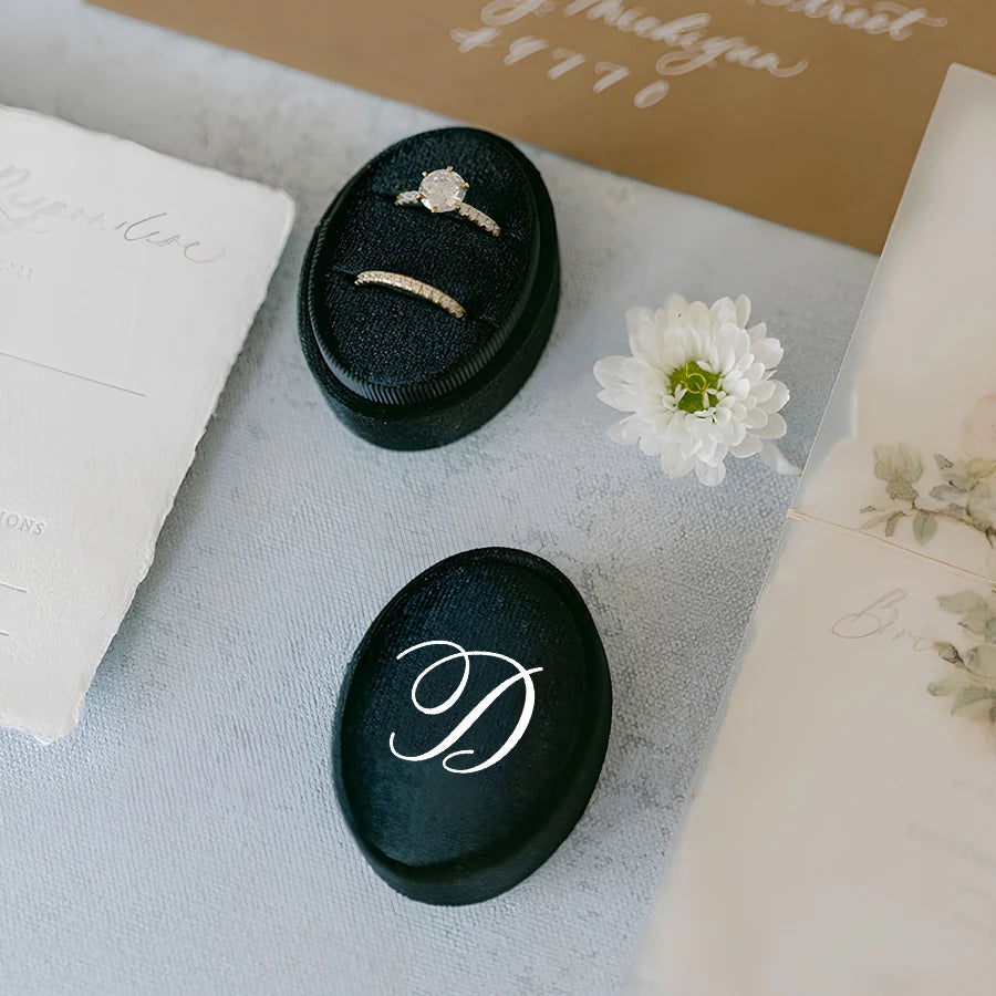 Black velvet ring box with engagement ring and matching band on insert