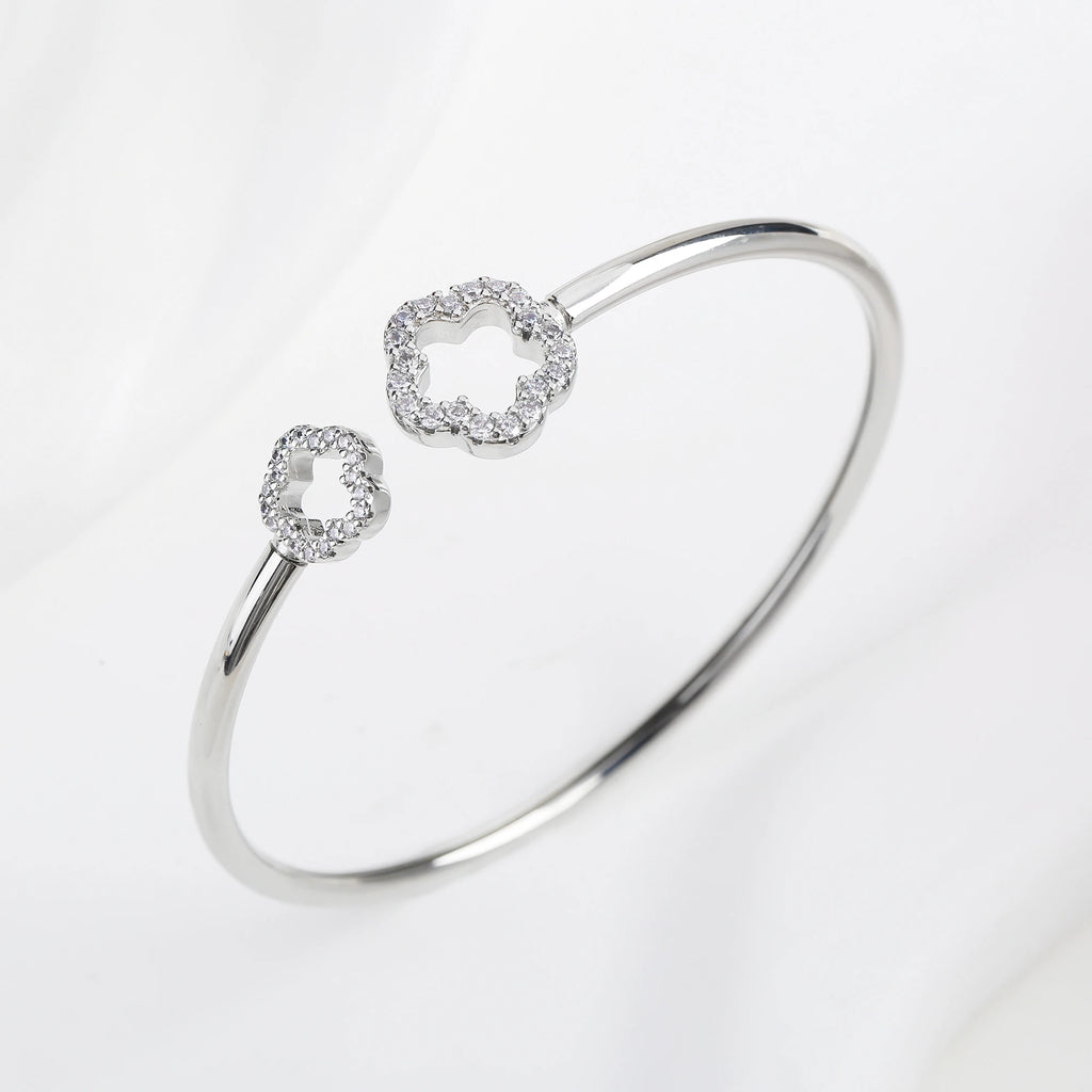 Silver open cuff bangle with two zirconia clover charms and a glossy open oval band