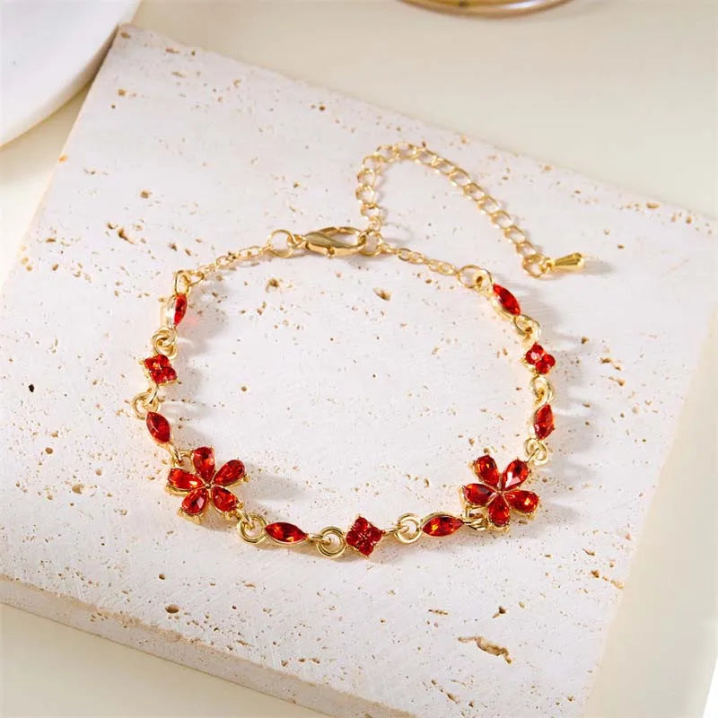 Gold-tone crystal flower bracelet with red blossom charms and teardrop stones