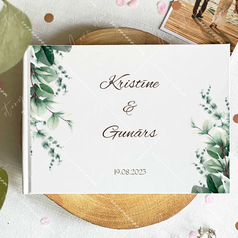 Wedding guest book cover with green eucalyptus sprigs on corners; names and date 19.08.2023