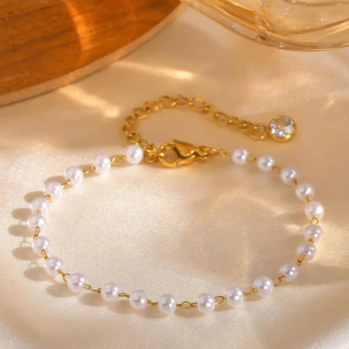 Gold pearl link bracelet with small round blue gemstone detail and white pearl strand